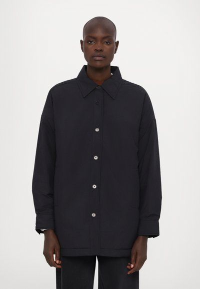 Námořnická modrá oversized bunda z lehké látky, s klasickým límcem, zapínáním na přední knoflíky a bočními kapsami.