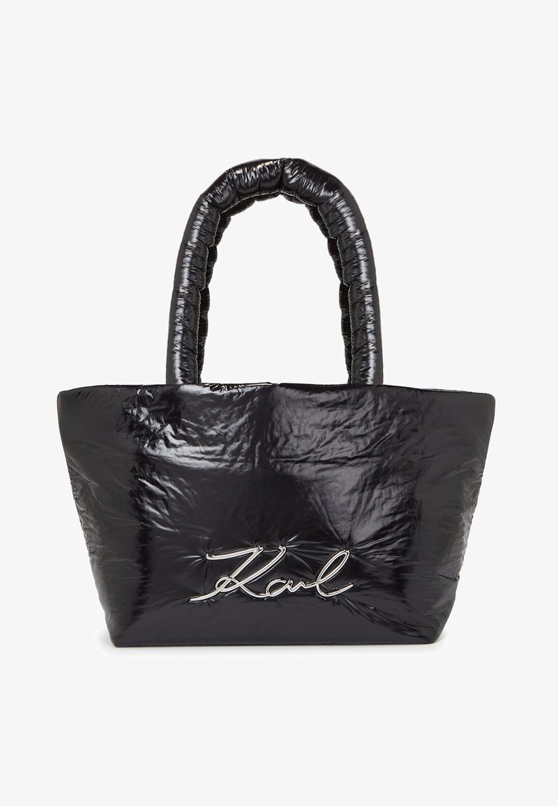 Černá nadýchaná taška přes rameno s texturovaným, lesklým materiálem a výrazným logem ve stříbrném písmu na přední straně. Obsahuje polstrovanou rukojeť.