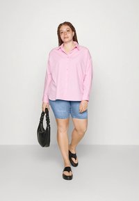 Ανοιχτό ροζ μακρυμάνικο πουκάμισο με κουμπιά, τζιν σορτς, μαύρα σανδάλια slide και μαύρη τσάντα ώμου. Καθημερινό ντύσιμο με άνετη εφαρμογή.