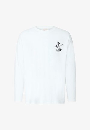 Άσπρο πουκάμισο με μακριά μανίκια, μικρό μαύρο λουλουδάτο σχέδιο και κείμενο στην αριστερή πλευρά του στήθους, στρογγυλή λαιμόκοψη, μονόχρωμο φόντο.