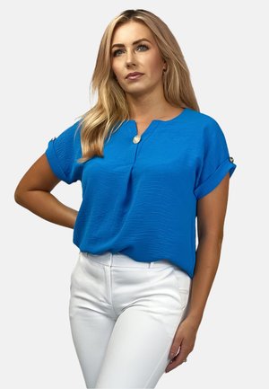 Blue short-sleeve top with a rounded neckline and a button detail at the chest, paired with white fitted pants. Smooth texture, casual fit.