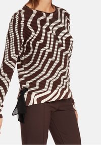 Brun- och vitrandig tröja med ribbad textur, med en sidoknytdetalj och glittrande accenter på bröstet.