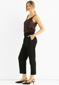 Black high-waisted pants paired with a sleeveless brown sequined top. The outfit includes black pointed-toe slingback heels.