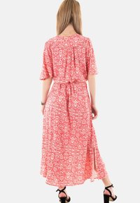 Vestido maxi rojo con estampado floral, de mangas cortas, con cintura ceñida y dobladillo con abertura lateral. Tejido ligero con una textura sutil.