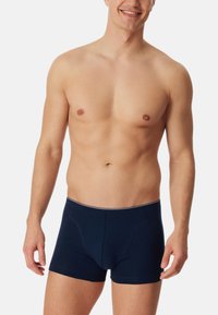 Marineblauwe katoenen boxershorts met een aansluitend ontwerp, gekenmerkt door contrasterende witte stiksels langs de tailleband en beenopeningen.