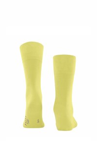 Gelbe knielange Socken mit glatter Textur. Verfügt über gerippte Bündchen und bedruckte Details am Knöchel. Hergestellt aus einem elastischen Stoff.