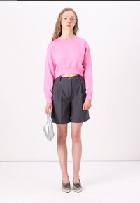 Rosa cropped sweatshirt, grå skreddersydde shorts, sølvveske og grå mønstrede sko. Glatte teksturer og moderne passform.