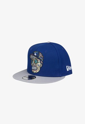 Blaues Cap mit grauem Schirm, das ein gesticktes Schädelmotiv mit lebendigen Farben und Mustern zeigt. Mit Logo an der Seite.