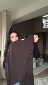 Hnedý, voľne strihnutý textilný top s jemnou textúrou. Má okrúhly výstrih a splývavý dizajn, s nerovnomerným lemovaním pre pridanie štýlu.