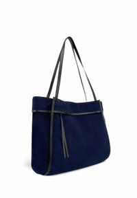Sac fourre-tout en daim bleu marine avec garniture en cuir noir et deux anses. Il présente un design plat avec des pampilles décoratives et des détails métalliques minimalistes.