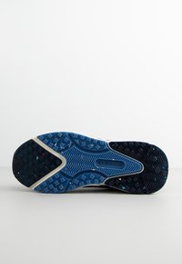 Rubber sports shoe sole with a wavy pattern, featuring a blue base, black edges, and colorful speckles. Textured for grip and durability.