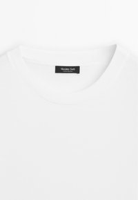 Weißes Baumwoll-T-Shirt mit einem gerippten Rundhalsausschnitt. Das Etikett zeigt "Massimo Dutti" an, was auf Herkunft aus Portugal hinweist. Glatte Textur und schlichtes Design.