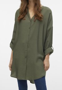 Camicia verde oliva con bottoni, dalla vestibilità comoda, maniche lunghe arrotolate ai polsini, realizzata in tessuto leggero e testurizzato, con scollatura a V.