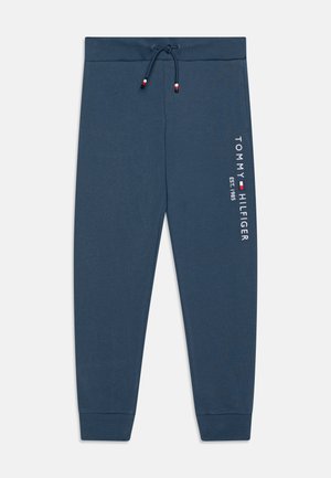 Mornarsko modre trenirka s vrvico v pasu, z logotipom "TOMMY HILFIGER" in letnico "EST. 1985" natisnjenima v beli barvi. Mehka tekstura, ožji kroj.