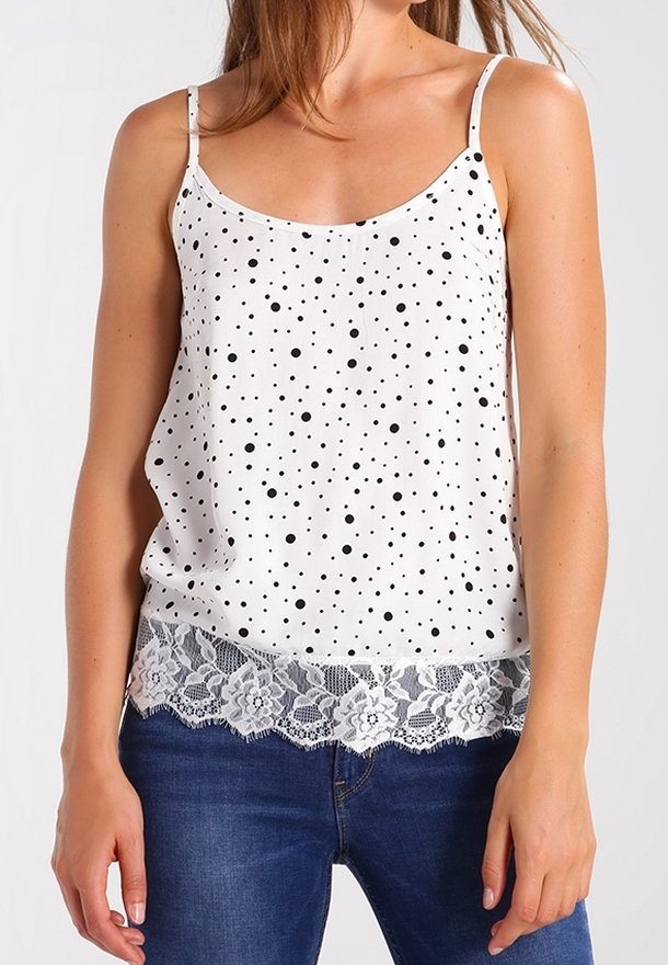 Top sin mangas blanco con lunares negros, con un delicado borde de encaje en la parte inferior. Tejido suave con un corte relajado.