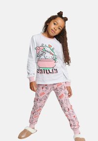 White long-sleeve pajama top with a colorful cartoon print and pink accents, paired with pink patterned pants featuring characters and hearts.
