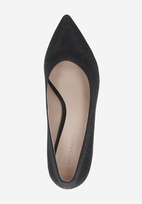Escarpin noir à bout pointu avec une tige texturée, doté d'une découpe sur le côté pour un design unique, doublure lisse et branding minimaliste à l'intérieur.