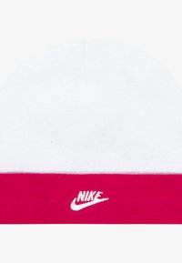 Κόκκινο και λευκό πλεκτό σκουφάκι με αντίθετη ροζ ζώνη και λευκό λογότυπο Nike. Μαλακή υφή, στρογγυλή μορφή και σχεδιασμός χωρίς ραφές στην κορυφή.
