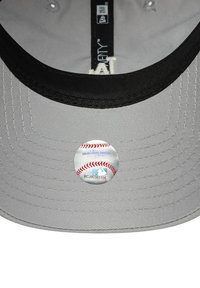 Sivi bejzbol kapa s crnim vizorom. Ima kružni MLB hologram naljepnicu na donjoj strani vizora. Teksturna tkanina.