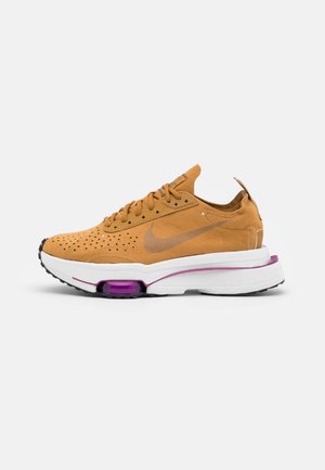 Baskets Nike marron avec dessus en daim perforé, semelle blanche avec coussin d'air violet visible, vue de côté sur fond blanc.