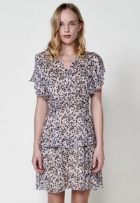 Kurzärmliges, leopardprint Kleid aus transparentem Stoff. Verfügt über einen V-Ausschnitt und geschichtete Rüschen an den Ärmeln und dem Saum in neutralen Tönen.