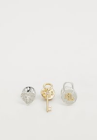 Tres accesorios de metal: a la izquierda hay un candado en forma de corazón plateado con rhinestones, en el centro hay una llave dorada con una base circular y a la derecha hay un candado plateado con "RL".