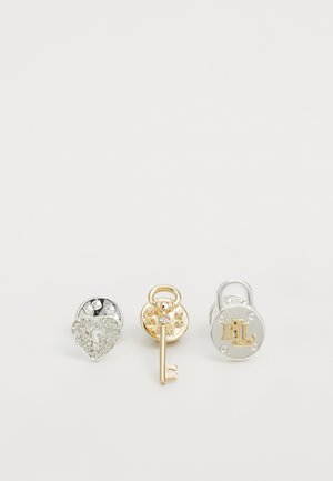 Three metal accessories: left is a silver heart lock with rhinestones, center is a gold key with a circular base, right is a silver padlock with "RL."