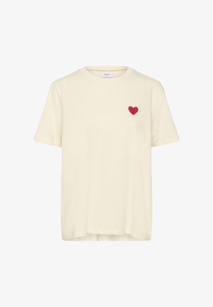 Kremowa bawełniana koszulka z okrągłym dekoltem i krótkimi rękawami, z małym czerwonym sercem na lewej stronie klatki piersiowej.