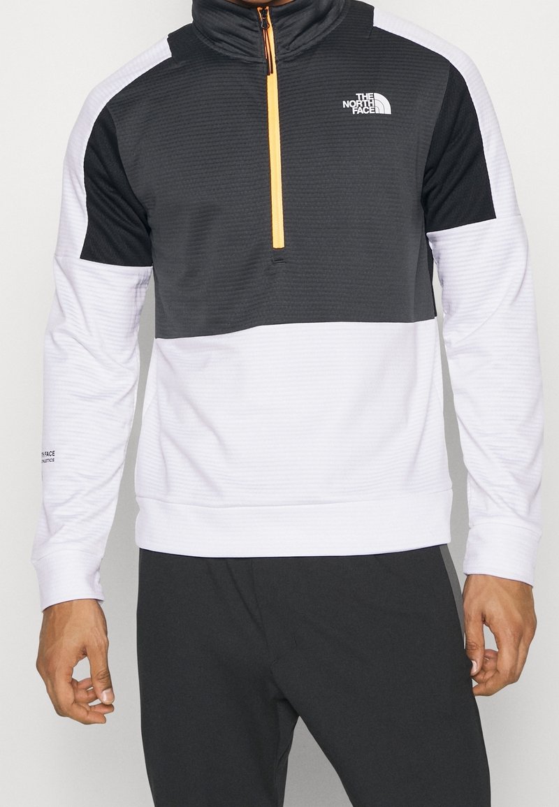 Pulóver de media cremallera para hombre en blanco y negro, con un diseño texturizado, acentos de color contrastantes y detalle del logo en el pecho y la manga.