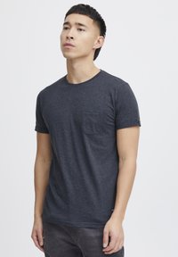 Mørkegrå kortærmet t-shirt lavet af blødt stof, med rund halslinje og brystlomme. Enkel, afslappet design med oprullede ærmer.
