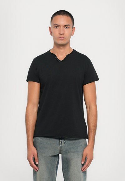 T-shirt nera a maniche corte con scollo a V e dettagli decorativi con bottoni nel collo. Realizzata in un tessuto leggero e morbido.