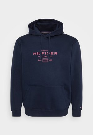 Navy blue Tommy Hilfiger hoodie with front pocket, adjustable hood, and pink logo text "Tommy Hilfiger New York City Est. 1985" on chest.
