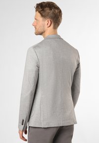 Grauer Blazer mit taillierter Passform, strukturiertem Stoff, Reverskragen und Details mit drei Knöpfen an den Ärmeln. Sauberes Design ohne zusätzliche Verzierungen.
