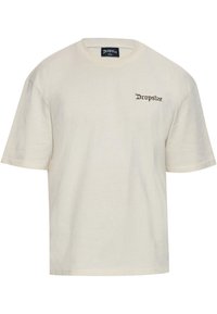 Cremefarbiges Baumwoll-T-Shirt mit lockerem Schnitt. Mit kurzen Ärmeln und einem kleinen braunen "Dropsize"-Logo, das auf der linken Brust gestickt ist.