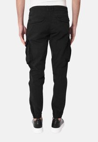Pantaloni cargo neri con tasche laterali, polsini elasticizzati e vestibilità rilassata. Realizzati in tessuto resistente con una finitura opaca.