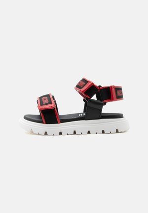Sort og rød open-toe sandal med justerbare remme og hvid kraftig sål, afslappet sportstil.