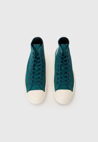 Hochschnittige Sneakers aus tealfarbenem Stoff mit einer weißen Gummikappe, ausgestattet mit Metallösen und passenden Schnürsenkeln. Weiche Textur und schlankes Design.