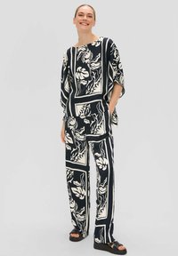 Twee-delig outfit bestaande uit een losse top en wijde broek in een donkere kleur met witte bloemen- en geometrische patronen. Zacht materiaal en een ontspannen ontwerp.