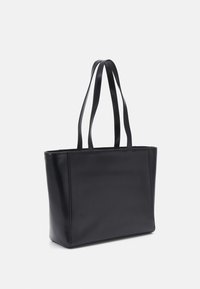 Svart tote-väska gjord av mjukt läder, med två platta handtag, rektangulär form och utan synlig hårdvara eller mönster.