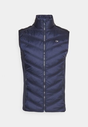 Chaleco acolchado de color azul marino con cuello alto y costuras en forma de chevron, con una cremallera frontal y un pequeño logo en la parte superior izquierda.