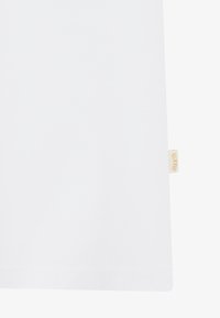 Weißes Baumwoll-T-Shirt mit geradem Saum, ausgestattet mit einem kleinen beige-farbenen Branding-Etikett an der unteren Seite zur Identifizierung.