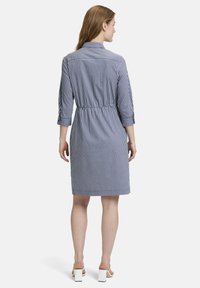 Abito a righe in navy e bianco, con vita belted, maniche a tre quarti e colletto classico, realizzato in tessuto leggero.