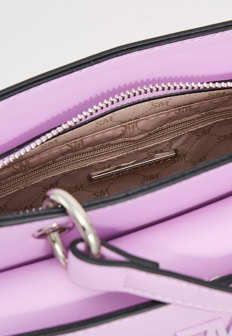 Sac à main synthétique rose avec une fermeture éclair. L'intérieur possède une doublure en satin et une poche zippée supplémentaire. Des accents noirs au niveau de l'ouverture.