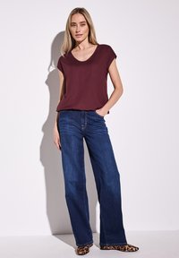 Haut bordeaux à manches courtes avec un col rond, associé à un jean en denim foncé à jambe large et des ballerines à bout pointu en imprimé léopard.