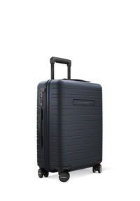 Valise rigide de couleur bleu foncé avec des rainures horizontales, poignée rétractable et quatre roues rotatives.  Équipée d'un cadenas à combinaison.