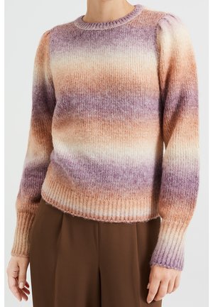 Femme portant un pull en tricot à manches longues avec des rayures dégradées horizontales aux tons violet, beige et orange, assorti à un pantalon marron.