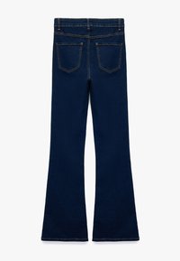 Donkerblauwe flared jeans met een klassiek vijf-pocket ontwerp, zichtbare stiksels en een nette tailleband. De textuur is gladde denim.