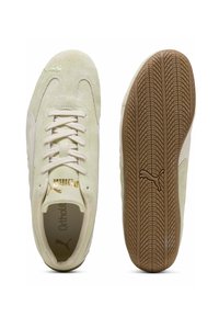 Zapatillas Puma con parte superior de ante verde claro, detalles en crema, cordones redondos, logotipo dorado y suela de goma marrón texturizada.