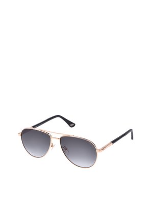 Une paire de lunettes de soleil aviateur avec des montures en métal rose doré et des verres dégradés noirs, avec des embouts de branches noirs.
