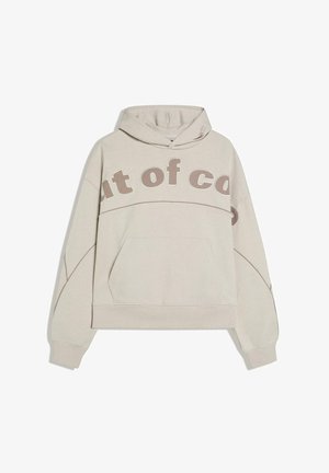 Light beige hoodie with kangaroo pocket, large hood, and partial bold text "out of co" across the chest and sleeves.